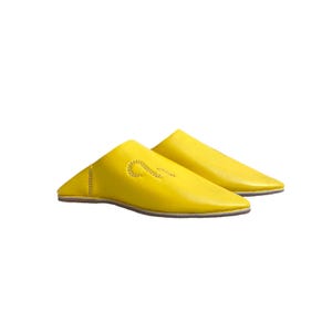 May include: A pair of yellow leather slippers with a pointed toe and a decorative stitch design.