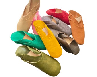 May include: Assortment of nine leather slippers in various colors, including green, yellow, brown, gray, and red. The slippers are arranged in a semi-circle on a white background.