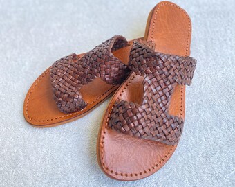 Peut inclure: Une paire de sandales en cuir marron avec un motif tissé. Les sandales ont deux lanières sur le dessus du pied.