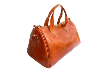 May include: A brown leather satchel bag with a top handle and a zipper closure.