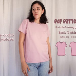 Puede incluir: Una persona modela una camiseta básica rosa claro con vaqueros azules. La imagen incluye el texto: "Pdf Pattern, illustrated sewing guide, Basic T-shirt, SIZES: XS - XXXL". El logotipo "Mercadito Moldes" también es visible.