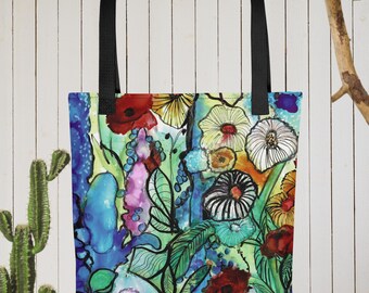 May include: A tote bag with a colorful floral design. The bag features a black handle and a vibrant watercolor painting of flowers in shades of red, yellow, blue, and green. The background is a light green.