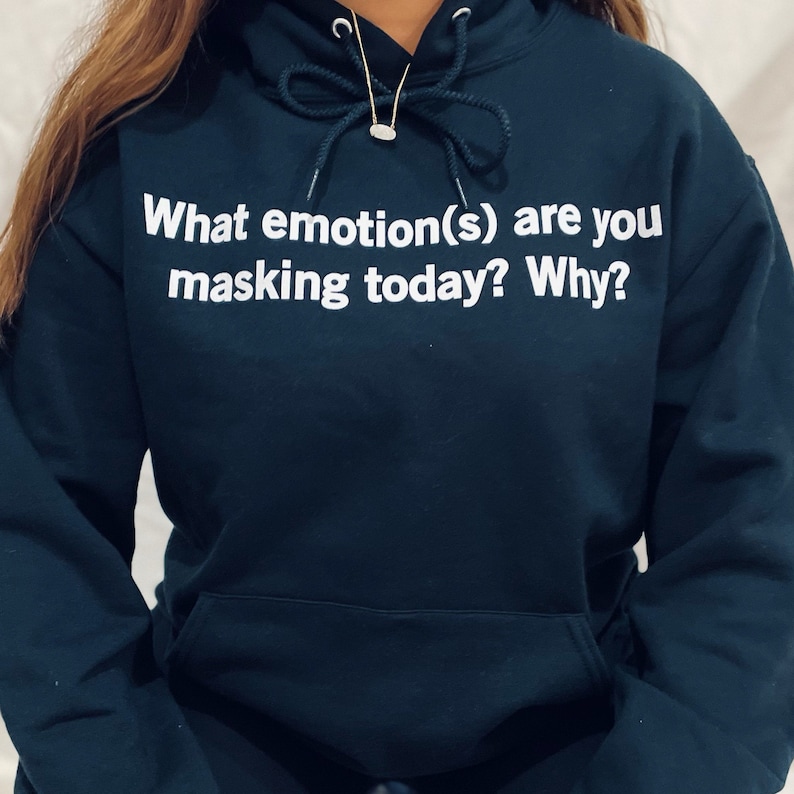 Może przedstawiać: Ciemnoniebieska bluza z kapturem z nadrukiem "What emotion(s) are you masking today? Why?" w kolorze białym.