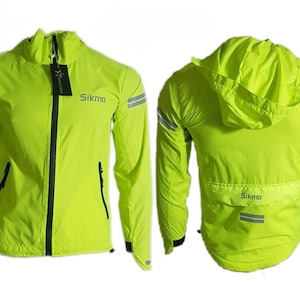 Puede incluir: Una chaqueta ligera de color amarillo brillante con capucha y detalles reflectantes. La chaqueta tiene cierre de cremallera y dos bolsillos. El nombre de la marca "Sikma" está impreso en la parte delantera y trasera de la chaqueta.