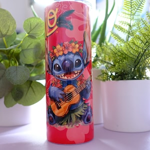 May include: A red tumbler featuring a cartoon character playing a ukulele, adorned with a floral lei. The design includes a tropical theme with a pink background and palm tree accents. The tumbler is cylindrical and appears to be made of stainless steel.