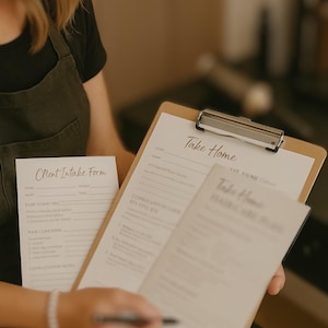 以下が含まれることがあります： 「Take Home」フォームと「Client Intake Form」が入ったクリップボードを持つ人。フォームは白地に黒文字。クリップボードは明るい茶色の木製。ペンがフォームの上に置かれています。