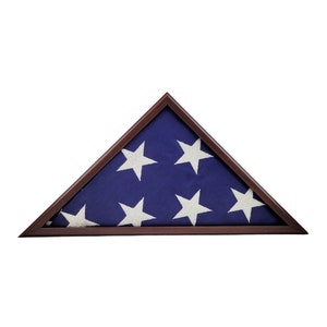 May include: A wooden triangular flag case with a folded American flag inside. The flag is blue with white stars.