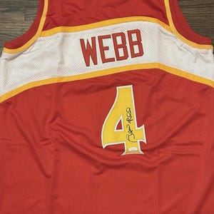 May include: Red basketball jersey with white and yellow detailing. The name "WEBB" is across the shoulders in red block letters. The number "4" is on the back in yellow with a signature. The jersey is made of a mesh material.