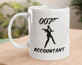 May include: White ceramic coffee mug with a black silhouette of a man holding a gun and the text "007" and "ACCOUNTANT".
