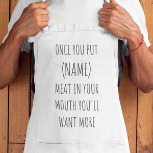 May include: White apron with the text "Once you put (NAME) meat in your mouth you'll want more".
