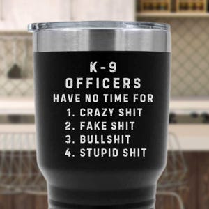 May include: Black stainless steel travel mug with a silver rim and lid. The mug has the text "K-9 OFFICERS HAVE NO TIME FOR 1. CRAZY SHIT 2. FAKE SHIT 3. BULLSHIT 4. STUPID SHIT" in white block letters.