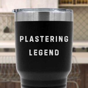 May include: Black insulated tumbler with a silver rim and lid. The words "PLASTERING LEGEND" are printed in white, bold, capital letters on the front of the tumbler. The tumbler is designed to keep beverages hot or cold.