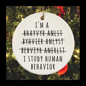May include: White ceramic Christmas ornament with black text that reads "I'm a Behavior Analyst. I study human behavior." The text is written in a playful way with the word "behavior" spelled incorrectly in the first three lines.