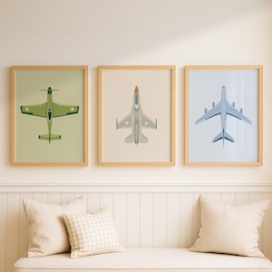 Puede incluir: Tres impresiones enmarcadas de arte de aviación. Las impresiones presentan vistas aéreas de diferentes aviones. El primero es un avión de combate verde, el segundo es un jet gris con una nariz naranja y el tercero es un avión de pasajeros azul.