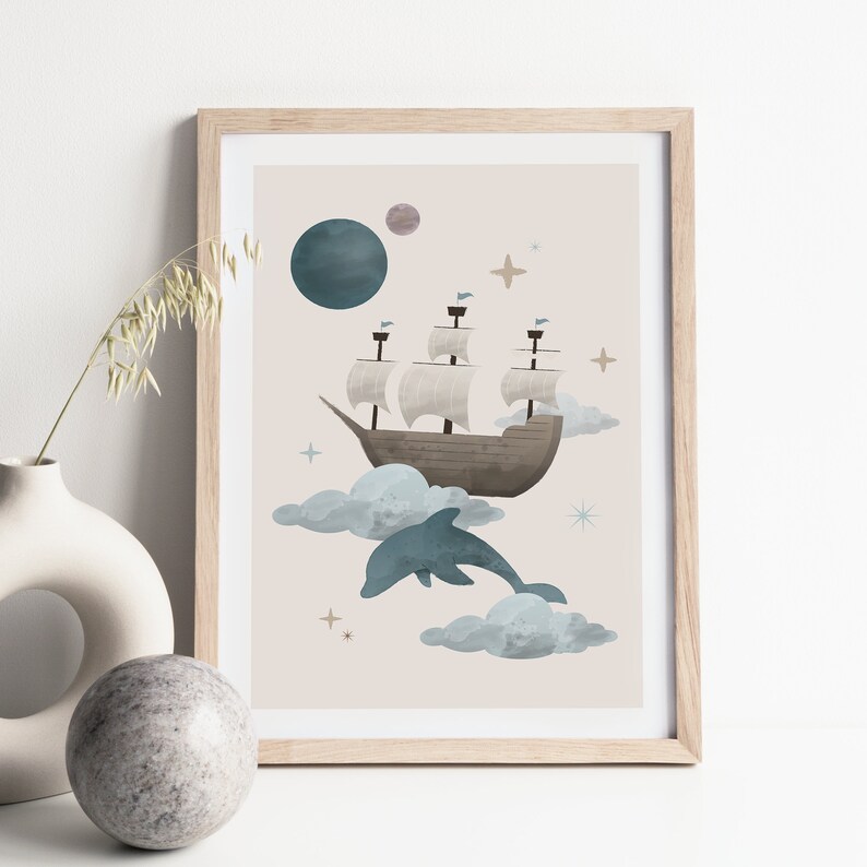May include: A framed print featuring a whimsical illustration of a ship sailing on clouds with a dolphin leaping out of the water. The background is a light beige with stars and a blue planet.
