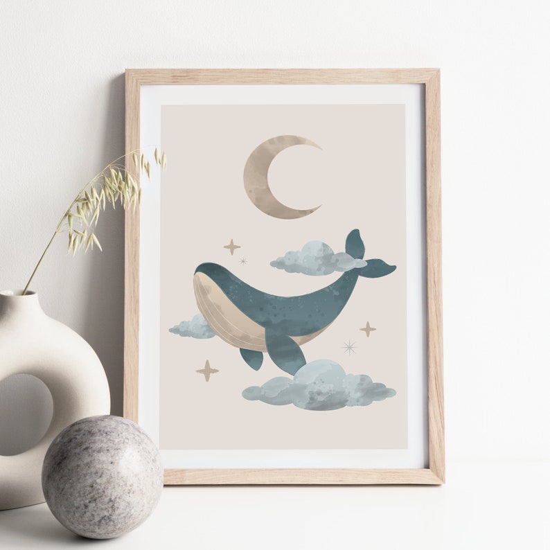 May include: A framed print with a light brown background featuring a blue whale swimming in the clouds with a crescent moon and stars.