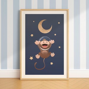 Peut inclure: Une affiche encadrée représentant un singe de dessin animé avec un casque spatial flottant sur un fond bleu foncé. Un croissant de lune doré et des étoiles entourent le singe. Le cadre est marron clair, et le fond est un mur à rayures bleues et blanches.