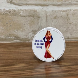 May include: White round phone grip with a cartoon image of a woman in a red dress and blue gloves. The text "I'm not bad... I'm just drawn that way" is printed on the grip.