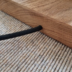 May include: A wooden lamp base with a black cord. The base is made of natural wood and has a rustic look. The cord is wrapped in black fabric.