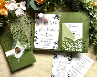 May include: Olive green wedding invitation suite with floral accents. The invitation includes the names Ashley Elizabeth & Kevin Mathew, and the date March 1, 2024. Additional cards include a response card, schedule of events, and accommodations.