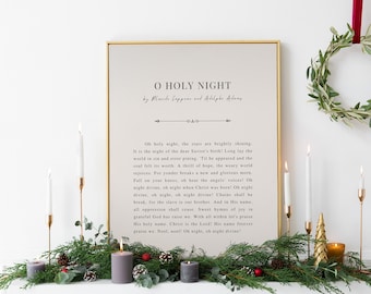 May include: A framed print of the lyrics to the Christmas carol "O Holy Night" by Placide Cappeau and Adolphe Adam. The print is displayed on a white mantel with a green garland, gold candlesticks, and a small gold Christmas tree.