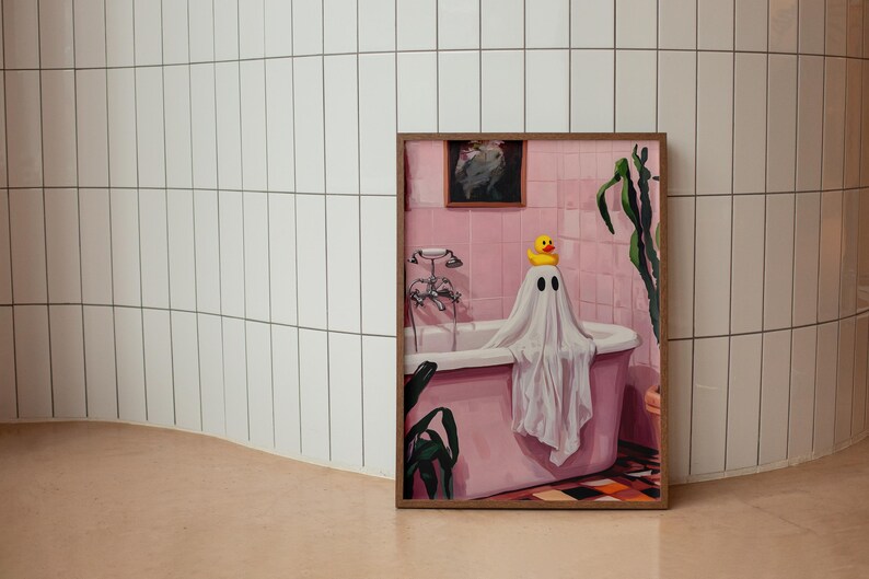 K&ouml;nnte beinhalten: Ein gerahmtes Kunstwerk zeigt eine rosa Badeszene mit einer Geisterfigur in einer Badewanne. Eine gelbe Quietscheente sitzt auf dem Kopf des Geistes. Das Kunstwerk ist vor einer wei&szlig; gefliesten Wand und einem hellbraunen Boden platziert.