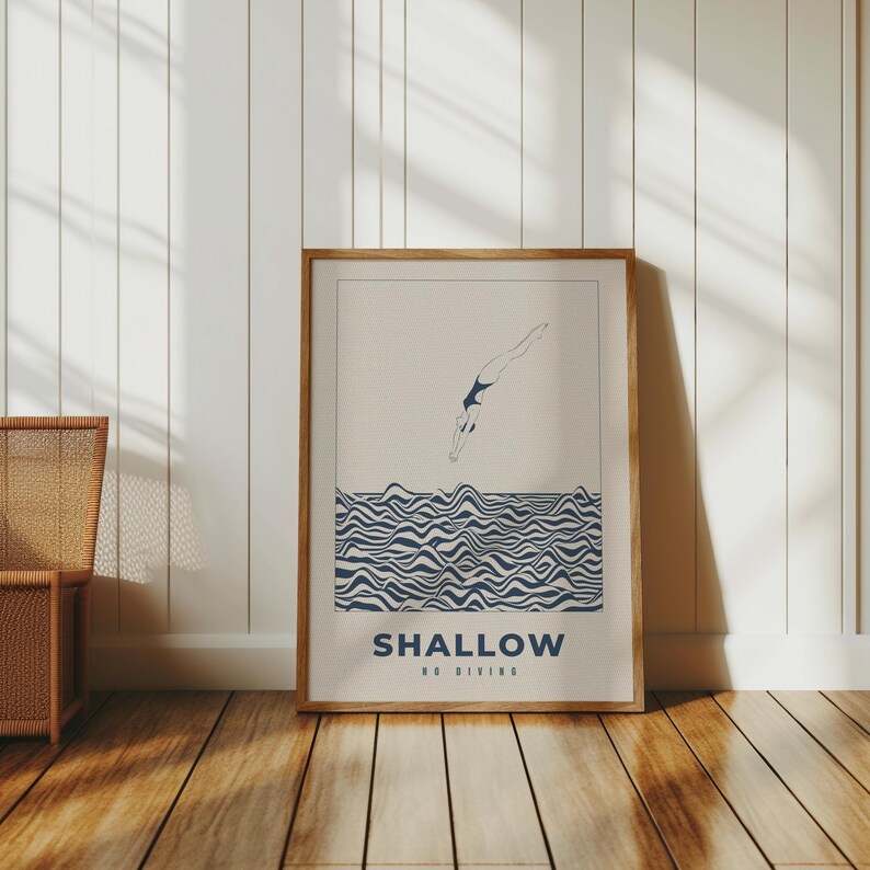 Op de afbeelding: Een ingelijste print met een minimalistische illustratie van een persoon die in golvend water duikt. De tekst "SHALLOW NO DIVING" is onder de illustratie gedrukt.