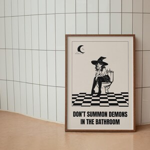 Peut inclure: Une illustration en noir et blanc d'une sorci&egrave;re assise sur des toilettes avec le texte "Ne pas invoquer des d&eacute;mons dans la salle de bain".