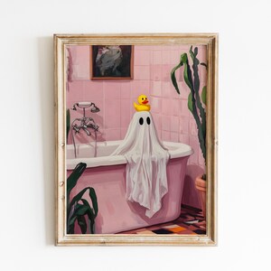 K&ouml;nnte beinhalten: Ein gerahmter Kunstdruck zeigt einen Geist in einem rosa Badezimmer, der in einer Badewanne mit einer gelben Gummiente auf dem Kopf sitzt. Das Badezimmer hat rosa Fliesen, ein gerahmtes Bild und eine Pflanze. Das Kunstwerk hat ein skurriles, gruseliges Thema.