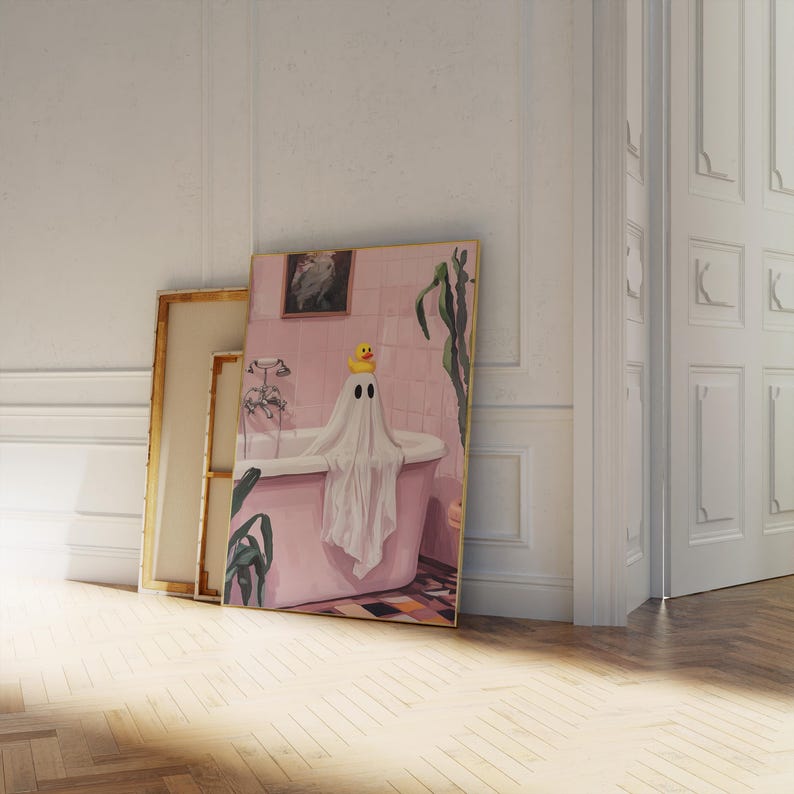 K&ouml;nnte beinhalten: Ein gerahmtes Kunstwerk zeigt einen Geist in einer rosa Badewanne mit einer Quietscheente. Der Geist ist in ein wei&szlig;es Laken geh&uuml;llt. Das Badezimmer hat rosa Fliesen und ein gerahmtes Bild.