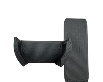 Puede incluir: Un soporte para teléfono negro impreso en 3D con un diseño curvo. El soporte está en dos piezas, una para el teléfono y otra para la base.