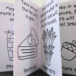 May include: A small, open book with black line drawings and text. The illustrations include a basket of apples, a slice of pie, corn stalks, and an acorn. Text includes Bible verses like "Taste and see that the Lord is good."