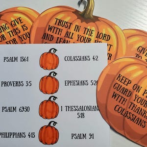 May include: Orange pumpkin-shaped cutouts with black text of Bible verses. A white card features orange pumpkin illustrations and Bible verses. The pumpkins have green stalks. The theme is Thanksgiving and faith.