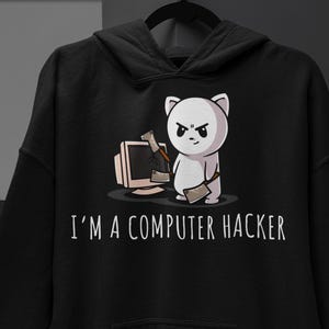 May include: A black hooded sweatshirt featuring a graphic of a white cartoon cat holding a meat cleaver next to a damaged computer monitor. Below the graphic, the text reads I'M A COMPUTER HACKER in white capital letters. The hoodie has long sleeves.