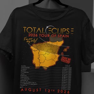 May include: Black t-shirt featuring a design for the 2026 Total Eclipse Tour of Spain. The graphic includes a map of Spain, the words "Total Eclipse," and the date "August 12th, 2026." Includes a list of cities.