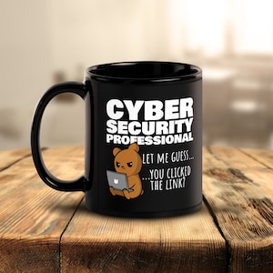 Könnte beinhalten: Schwarze 312g-Tasse mit dem Text "CYBER SECURITY PROFESSIONAL" und einem Cartoon-Bären, der einen Laptop benutzt. Die Tasse hat einen gebogenen Griff und den Text "LET ME GUESS... YOU CLICKED THE LINK?"