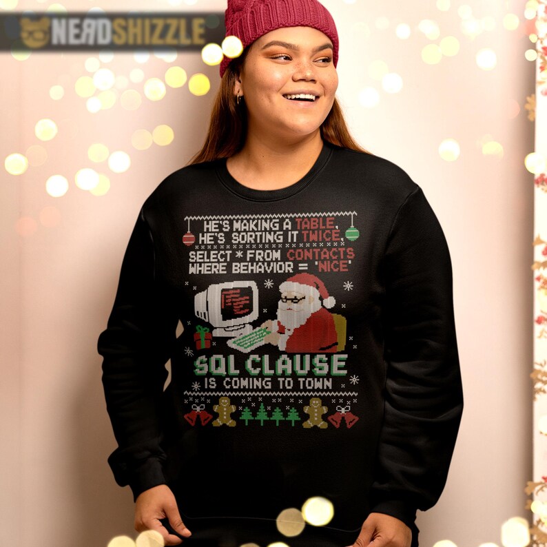 K&ouml;nnte beinhalten: Ein schwarzes Langarm-Sweatshirt mit einem Grafikdruck von Santa Claus an einem Computer. Der Text lautet: He's making a table, he's sorting it twice, select * from contacts where behavior = 'nice', SQL clause is coming to town.