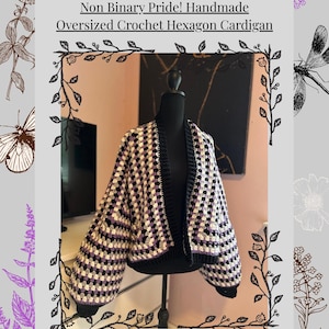 May include: Handmade oversized crochet hexagon cardigan in black, white, and purple. The cardigan is displayed on a mannequin. The text on the image reads "Non Binary Pride! Handmade Oversized Crochet Hexagon Cardigan."