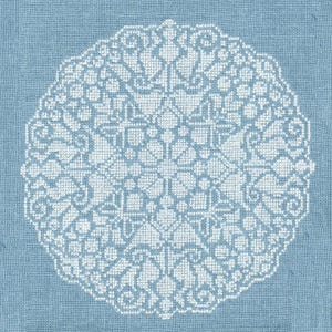 Puede incluir: Un tapete blanco de punto de cruz con un diseño simétrico y detallado. El tapete es circular y está sobre un fondo de tela azul claro. El intrincado patrón presenta formas geométricas y elementos florales, creando una apariencia delicada y ornamentada.