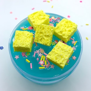 May include: Yellow sponge squares in a blue slime with pink and yellow sprinkles.