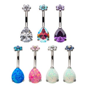 May include: A set of seven belly button rings with a flower design at the top and a teardrop-shaped gem at the bottom. The gems are in various colors, including clear, red, purple, blue, pink, and white.