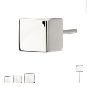 May include: A silver square-shaped stud earring with a post.