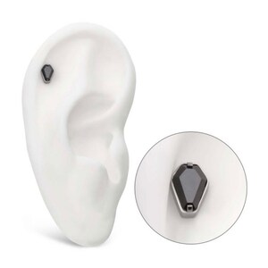 May include: A black gemstone ear cuff with a silver setting. The ear cuff is shown on a model ear.