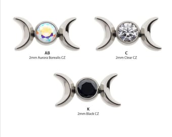 May include: Three silver triple moon body jewelry charms with different colored gemstones. The first charm has an iridescent aurora borealis gemstone, the second charm has a clear gemstone, and the third charm has a black gemstone. Each charm is labeled with a letter and the gemstone type. AB 2mm Aurora Borealis CZ, C 2mm Clear CZ, K 2mm Black CZ.