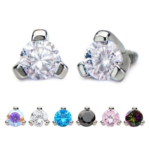 May include: Two silver-colored, triangular-shaped body jewelry pieces with a clear, round gemstone. Below are five additional pieces in various colors: iridescent, clear, blue, black, pink, and iridescent green.