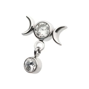Puede incluir: Colgante de triple luna de plata con dos piedras de cristal transparentes. El colgante está unido a una cadena de plata.