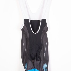 May include: Black cycling bib shorts with blue and white accents. The shorts have a white mesh panel on the back and the text "CYCLOCROSS x COLLECTIVE" on the side.