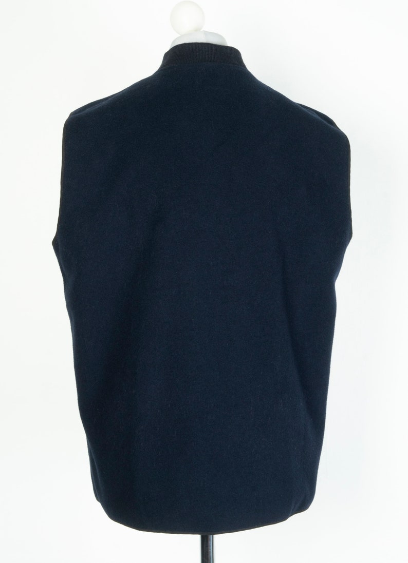 May include: A dark blue sleeveless sweater vest with a ribbed collar and a smooth texture.