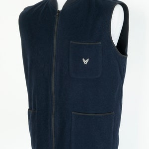 May include: A navy blue fleece vest with a zipper closure and two front pockets. The vest has a small embroidered logo on the left chest.