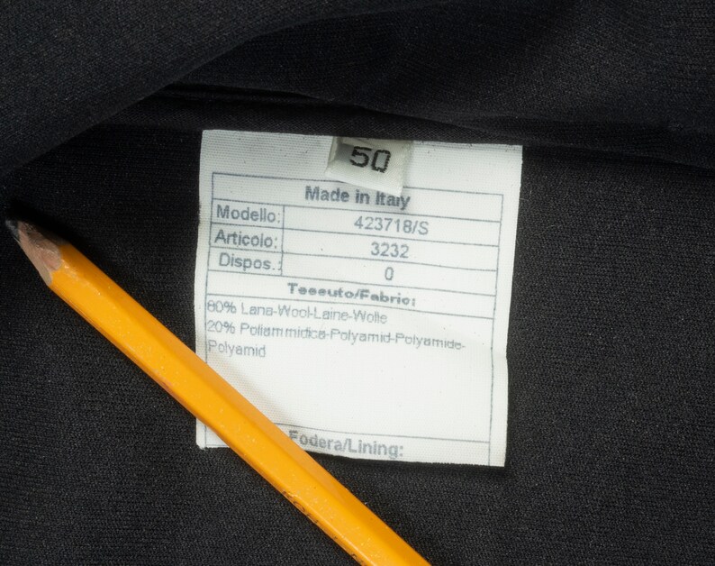 May include: A white tag with black text on a black fabric background. The tag lists the following information: Made in Italy, Modello: 423718/S, Articolo: 3232, Dispos: 0, Teseuto/Fabric: 80% Lana-Wool-Laine-Wolte, 20% Poliam midice-Polyamid-Polyamide-Polyamid, Fodera/Lining: